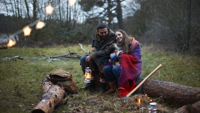 people sitting with dog at camp site