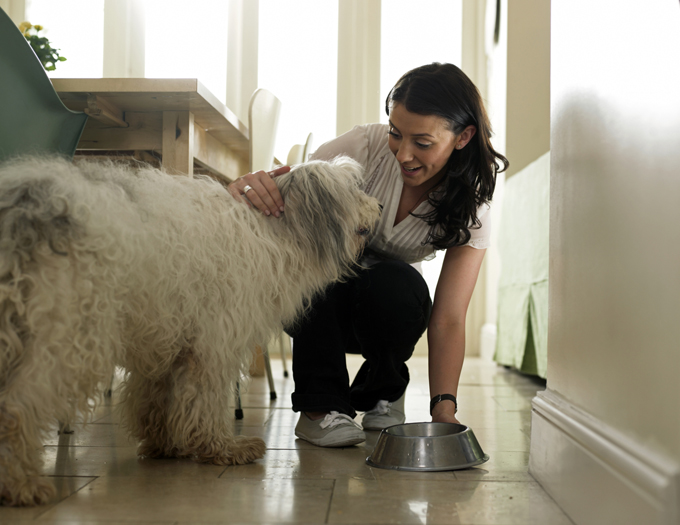 Woman putting water bowl down for her dog