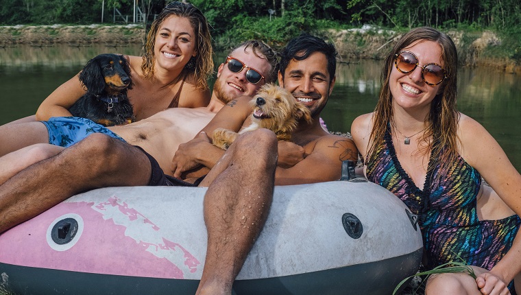 Two Adult Males with Two Adult Females and Two Dogs sitting in a floaty by Ponchatoula Creek after a day of tubing down the river in Southern Louisiana.