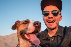 Happy young male person makes self portrait with his dog outdoors