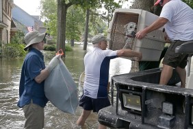 A father and son carry their dog as they evacuate from their homes the flood in Lakeside Estate in Houston, Texas on August 30, 2017. Monster storm Harvey made landfall again Wednesday in Louisiana, evoking painful memories of Hurricane Katrina's deadly strike 12 years ago, as time was running out in Texas to find survivors in the raging floodwaters. / AFP PHOTO / Thomas B. Shea (Photo credit should read THOMAS B. SHEA/AFP/Getty Images)