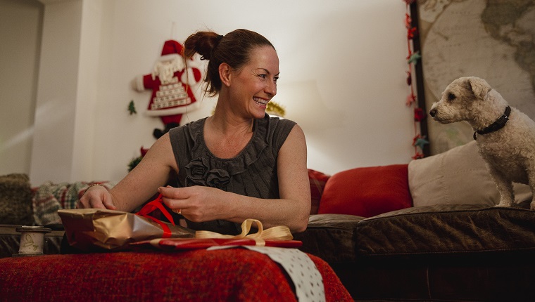 Mature woman wrapping Christmas presents at home.