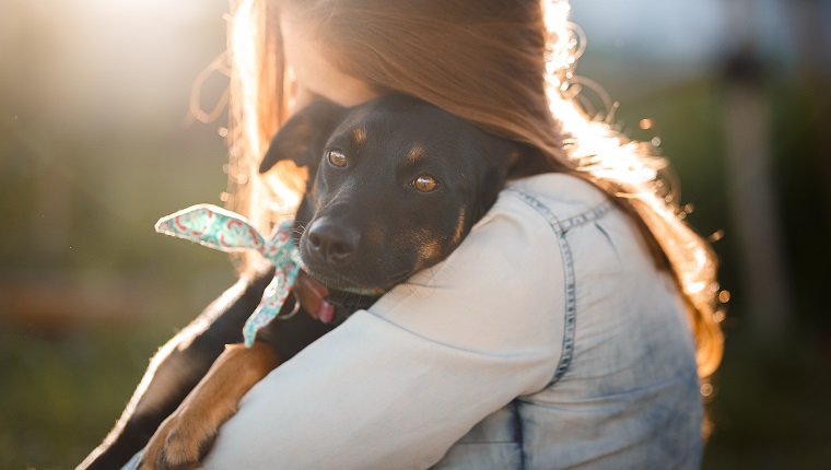 Girl hugging her cute black mutt dog