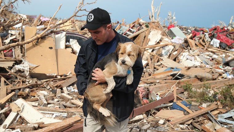 MOORE, OK - MAY 21: Sean Xuereb recovers a dog from the rubble of a home that was destroyed by a tornado on May 21, 2013 in Moore, Oklahoma. The town reported a tornado of at least EF4 strength and two miles wide that touched down yesterday killing at least 24 people and leveling everything in its path. U.S. President Barack Obama promised federal aid to supplement state and local recovery efforts.