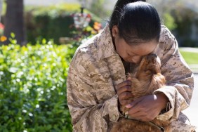 Female soldier hugging pet dog on street at homecoming