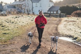 Mature Caucasian female on a rural track, out for an early morning jog with her two Dalmatian dogs.