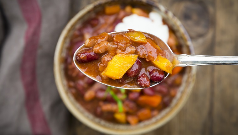 Chili con Carne with coriander and sour cream, spoon, close-up