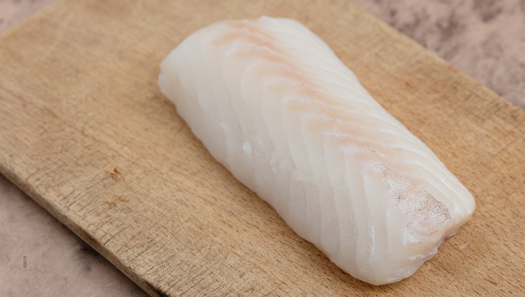 Codfish fillet on wooden board.