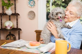 Senior woman holding dog at table