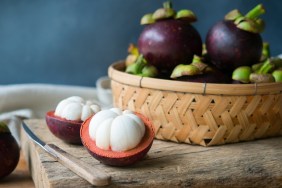 Fresh mangosteen Thai fruits cut in half on wooden table.