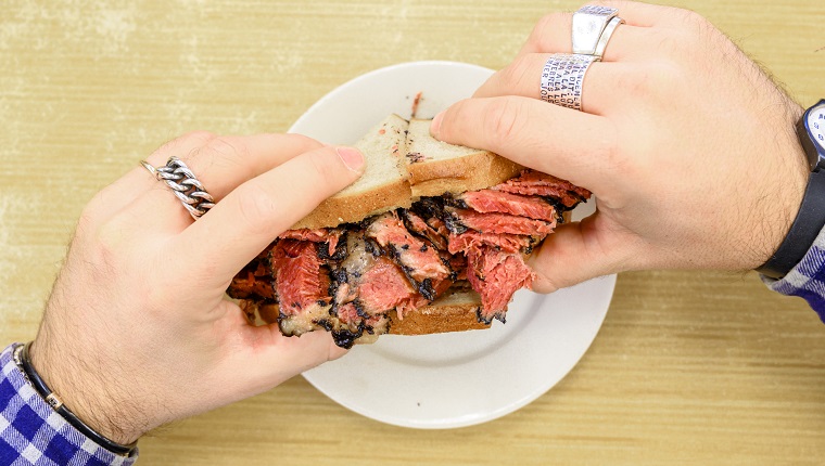 Personal perspective of man eating pastrami sandwich, New York City