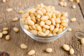 Pine nuts tasty, fresh, in glass bowl on wooden background (table) close up, horizontal