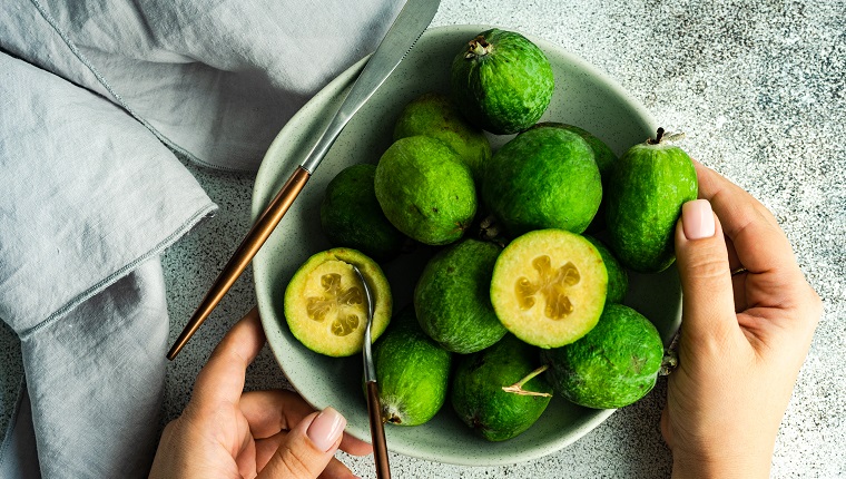 Organic and ripe feijoa fruits and woman hands as a healthy food concept