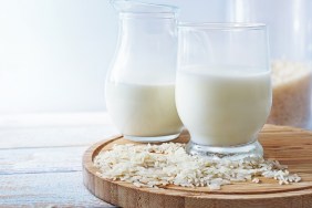 Vegan rice milk, healthy alternative without animal dairy products in a drinking glass and a jug on a wooden kitchen board against a light background, copy space, selected focus, narrow depth of field