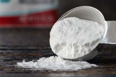 Close-Up Of Baking Soda Spilled From Measuring Spoon On Table