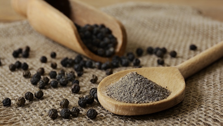 Ground Black Pepper and Peppercorns with wooden spoon and scoop. Studio shot on June, 18, 2018