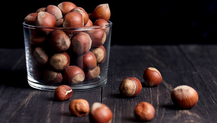 hazelnuts in shell in a transparent vase on a dark wooden table