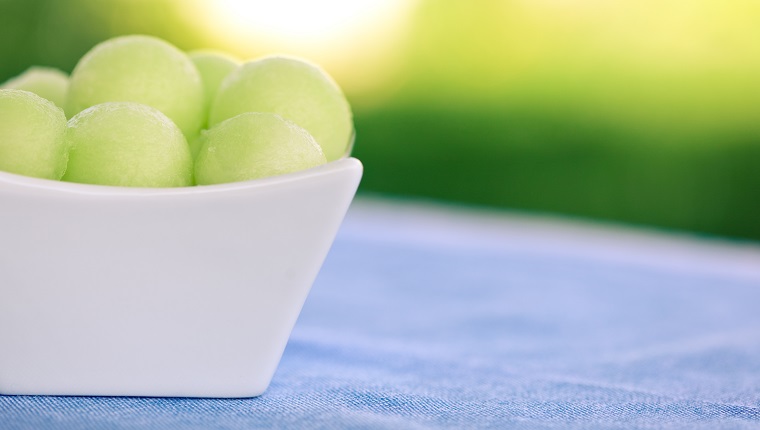 Honeydew melon balls in a white porcelain dish.