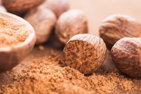 Ground nutmeg spice in the wooden spoon closeup