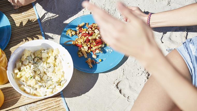 Two friends on the beach having a salad