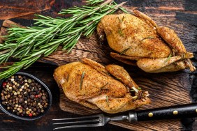 Homemade baked quail on a cutting board. Dark Wooden background. Top view.