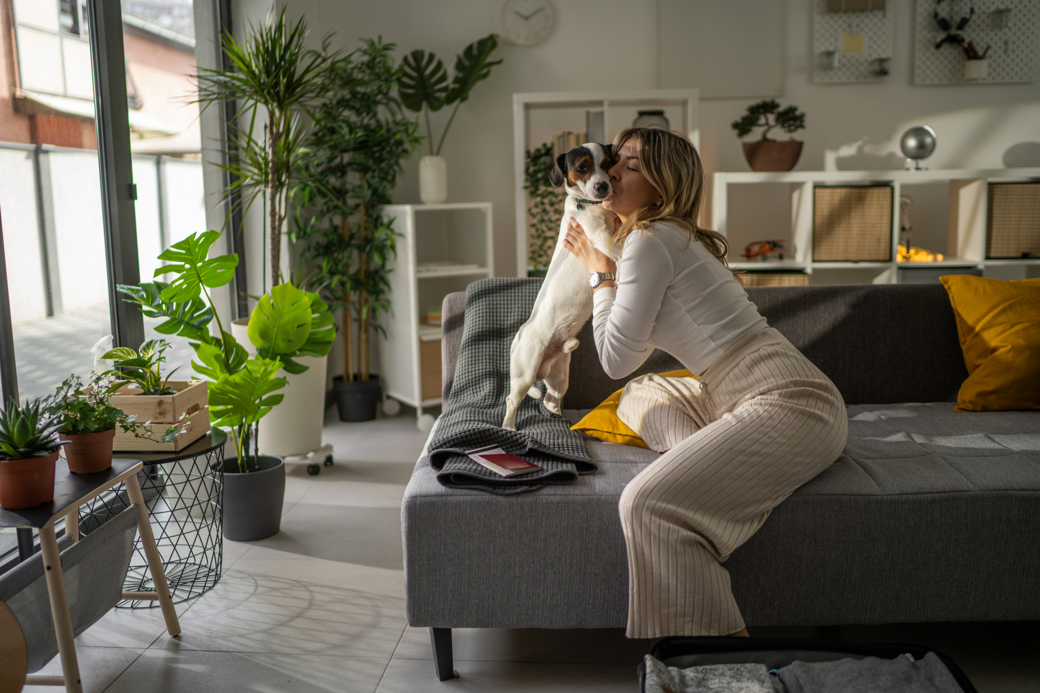 woman hugging dog on suitcase leaving your dog at home when you travel