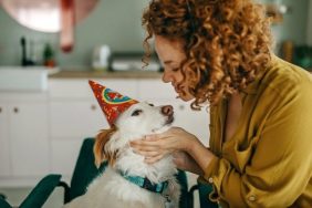 woman hugging dog in birthday hats codependent with dog