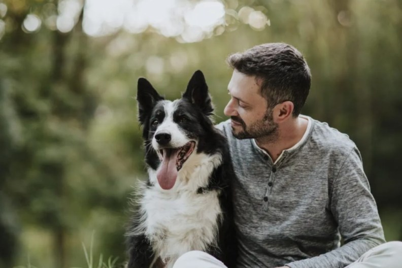 A Border Collie dog with a man in a forest, like the dog whose owner discovered a dinosaur skeleton while out on a walk.