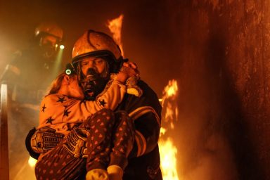 A firefighter holding a little girl in his arms, like the girl who was reported dead while trying save her dog from house fire.