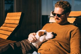 Man in sunglasses pet sitting dog on a wooden bench — cheap travel hack.