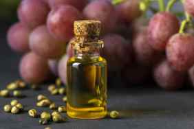 Grape seed oil in a glass jar and fresh grapes
