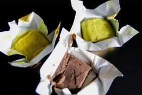 Three cubes of bouillon, which are not safe for dogs to eat, against a black background.