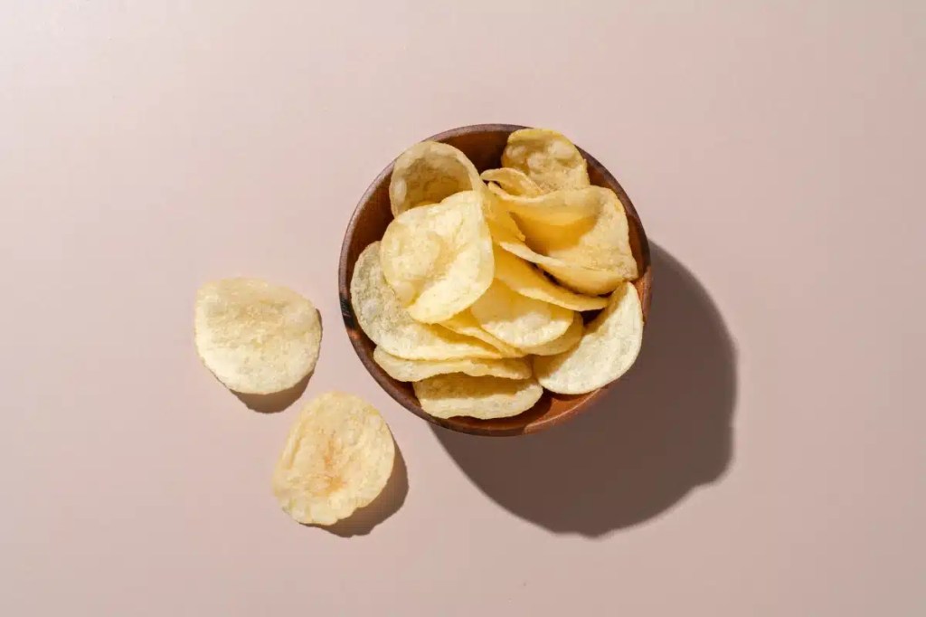 A bowl of potato chips, which dogs should not eat due to their salt, fat, and carb content. Although not toxic, there are safer treats for dogs.