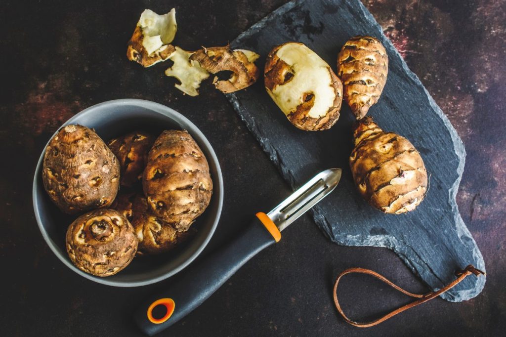 A photograph of Jerusalem artichokes on a slate cutting board. Dogs can eat Jerusalem artichokes if they are cooked.