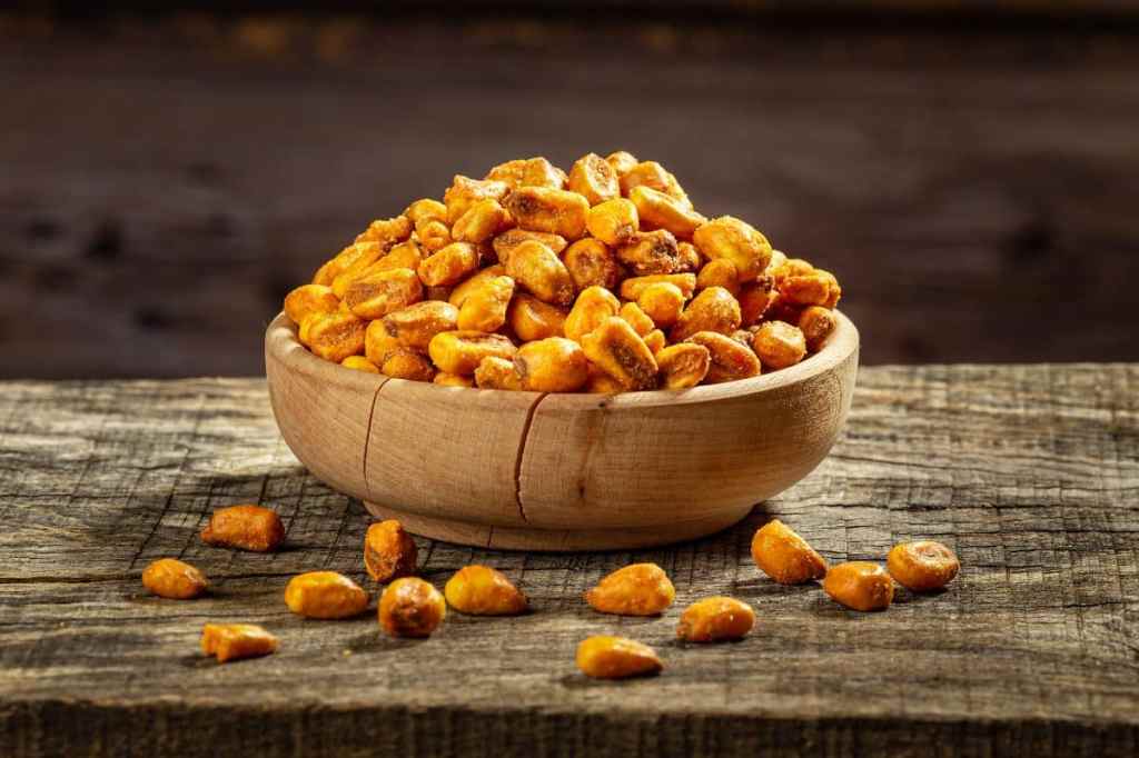 Bowl with roasted corn nuts on a wooden table.