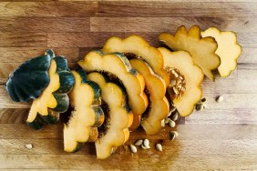 A photo of sliced acorrn squash, which is safe for dogs to eat if cooked, on a wooden cutting board.