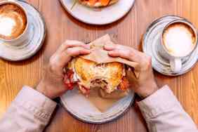 Person eating a bagel sandwich.