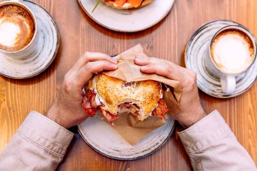 Person eating a bagel sandwich.