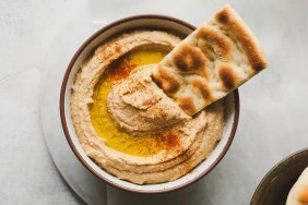 A closeup photo of pita bread and a bowl of hummus, which dogs should not eat due to seasonings containing garlic and onions.