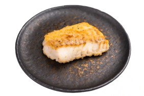 A photograph of a roast halibut filet, which dogs can safely eat if cooked and deboned, on a charcoal plate.