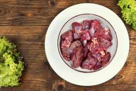 Raw steak meat from deer on table with ingredients on wooden rustic background.