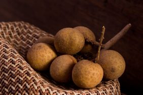A bunch of longan fruits on a wooden surface.
